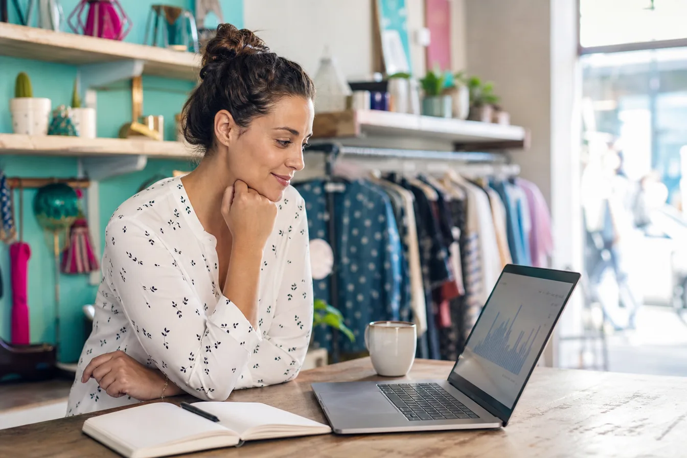Small business owner reviewing simple growth charts on a laptop at her shop counter — illustrative photo