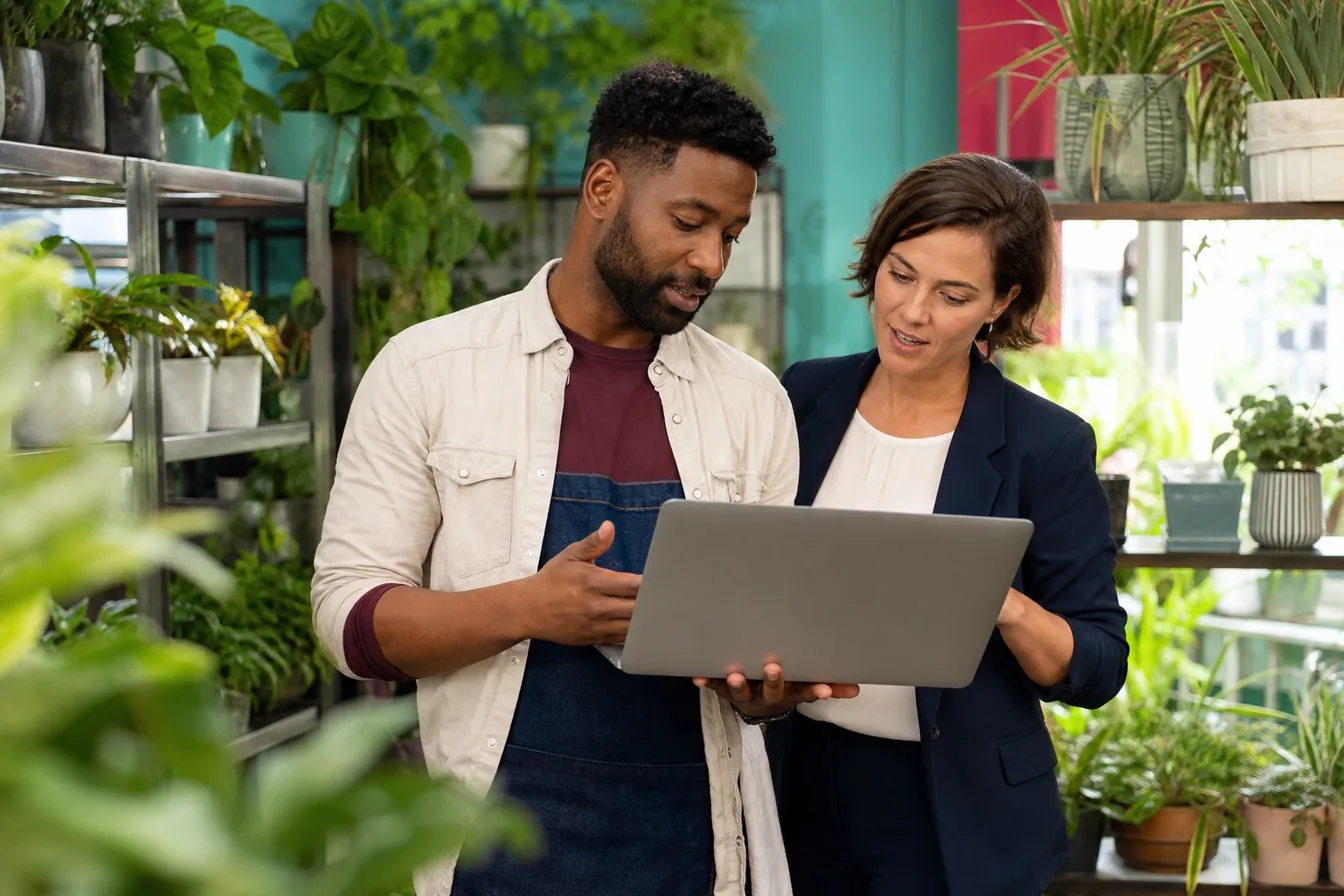 Consultant and plant shop owner reviewing a laptop together in the shop — illustrative photo